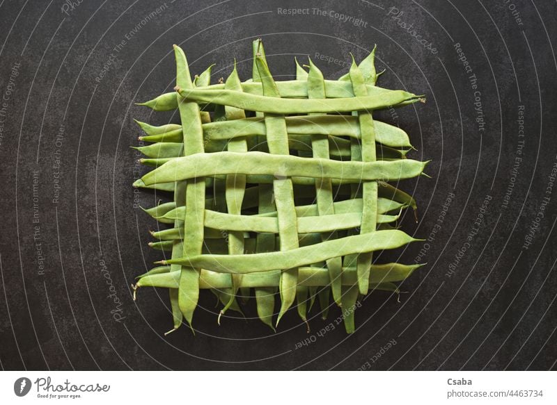 Top view of whole green beans in a geometric pattern on dark background shape vegetarian healthy food vegetable raw ingredient veggie top grid fresh ripe flat