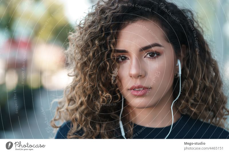 Young latin woman wearing earphones while standing outdoors. young listening street urban city lifestyle wireless expression serious outside youth using