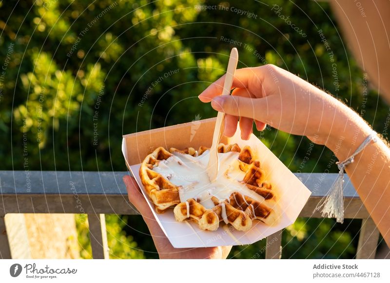 Anonymous person enjoying delicious waffles against mountains in sunshine eat dessert treat cream whipped sweet takeaway box spoon belgian tasty smooth aroma