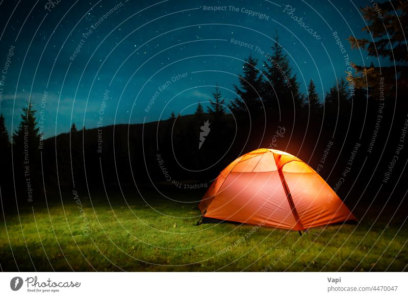 Illuminated tent in night forest mountains illuminated stars nature landscape red orange yellow outdoor light travel sky tree grass pine summer hiking camp