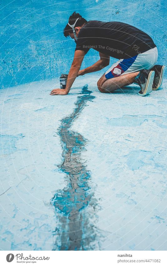 Young man working in his swimming pool maintenance diy mask putty putty knife putty palette blue turquoise job tools hard physical composition paint fix fixing