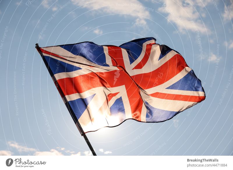 UK Great Britain flag waving in cloudy blue sky Flag banner United Kingdom British clear flying wave wind flagstaff flagpole closeup side view stars symbol