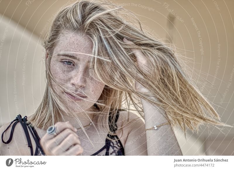 Young blonde girl with long straight hair isolated on white background next  to a plant, nature concept Stock Photo