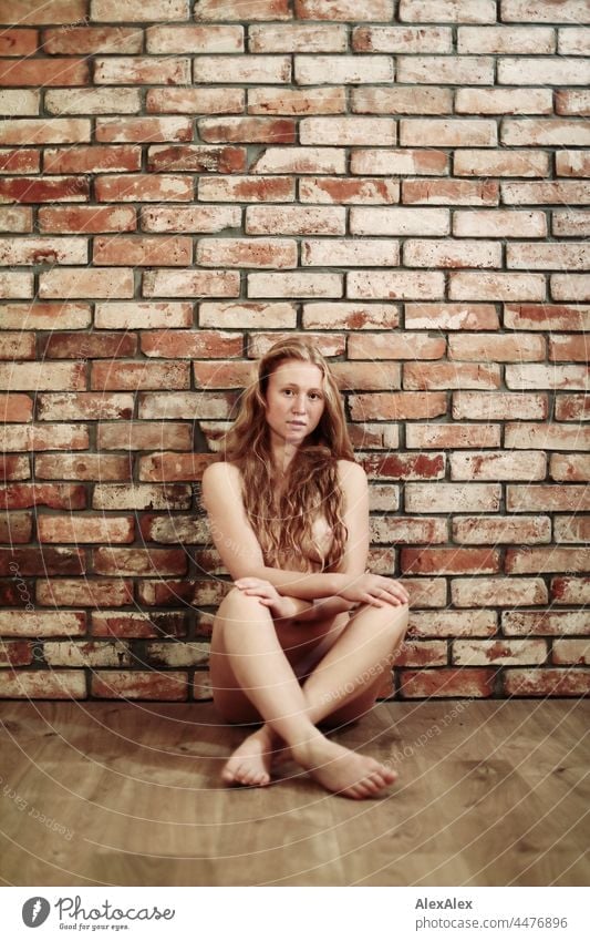 Full body image of a naked young woman with freckles and red hair