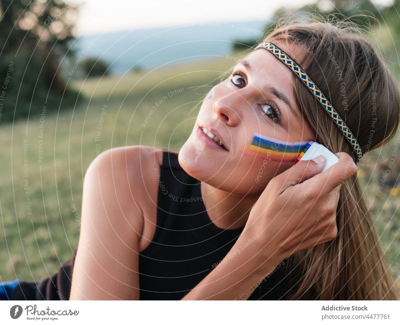 Woman painting rainbow on face with a stick hippie liberty lgtbi lgtbiq freedom lifestyles peace purple love magenta people retro lesbian color image colorful