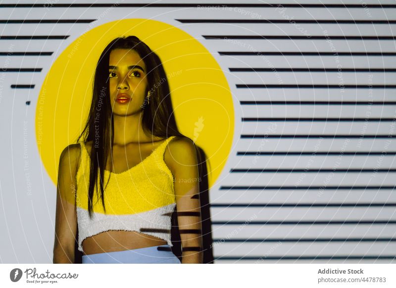 Tender ethnic model in crop top in projector light style contemplate pleasant appearance stripe woman millennial makeup hispanic cool parallel circle form