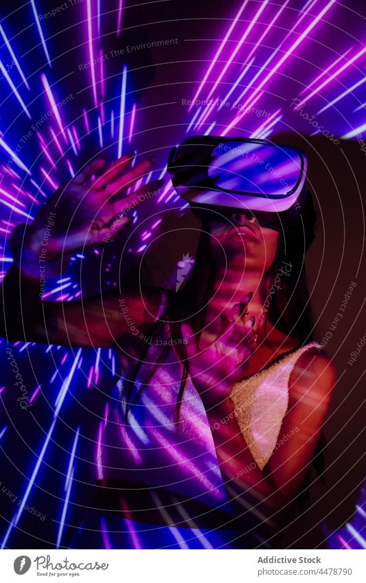 Woman in VR goggles in neon lights woman virtual reality immerse illumination experience entertain technology projector spare time using gadget vr headset