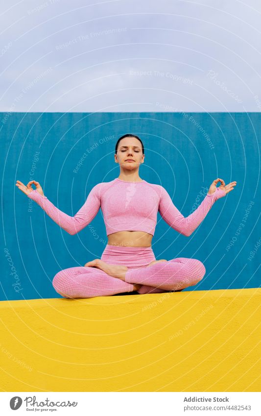 Calm woman sitting and meditating lotus pose calm meditate wellness harmony activewear peaceful practice zen female yoga relax healthy young asana exercise