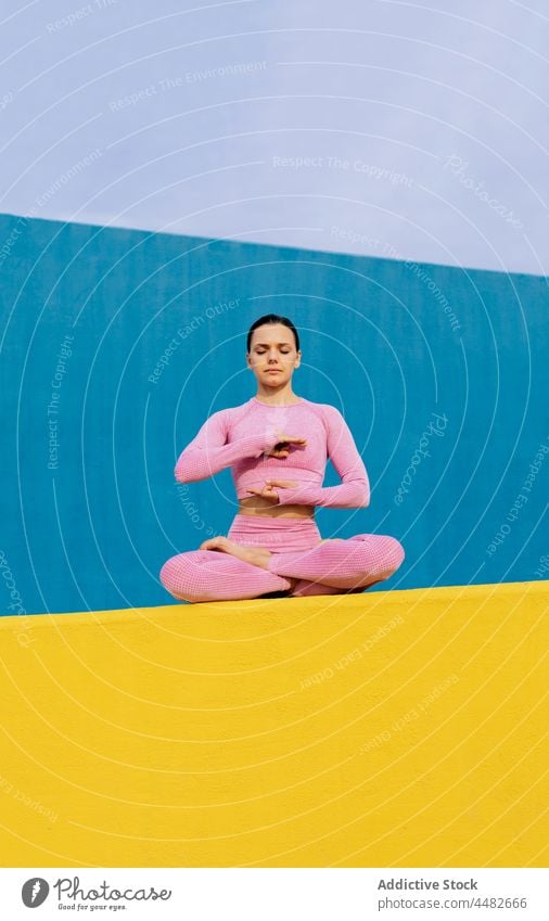 Tranquil woman meditating and doing yoga in Lotus pose meditate flexible padmasana vivid colorful lotus pose calm female zen stress relief breathe practice