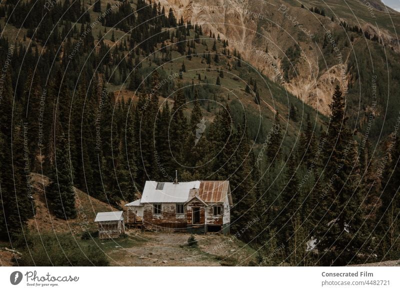 Abandoned house in the mountains abandoned house abandoned home Ghost town wrecked and ruined wood home vintage travel adventure trees dark moody mountain range
