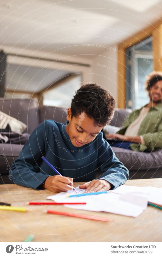 Boy drawing on paper on coffee table at home mixed race boy child art creativity concentrate learn indoors day interior two people portrait authentic content