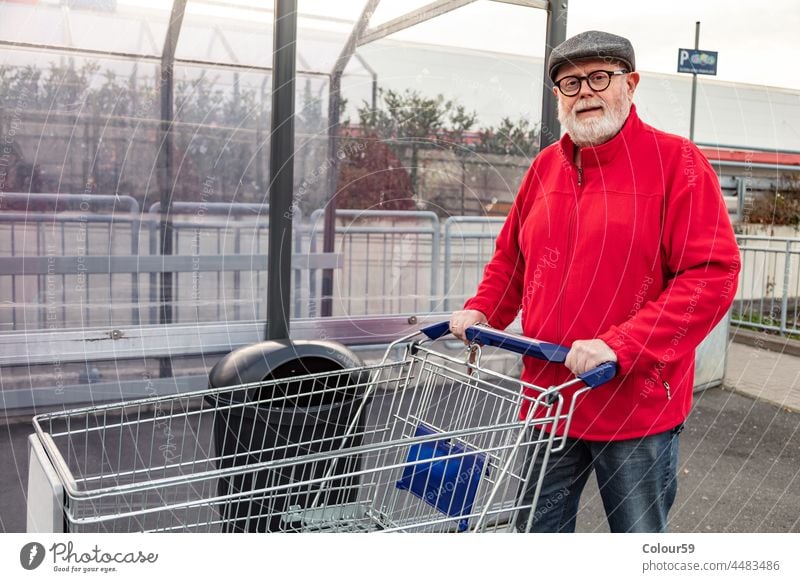 Senior pushing a shopping cart senior smiling optimistic retired grandfather man consumer male customer caucasian trolley person cheerful shopper one adult