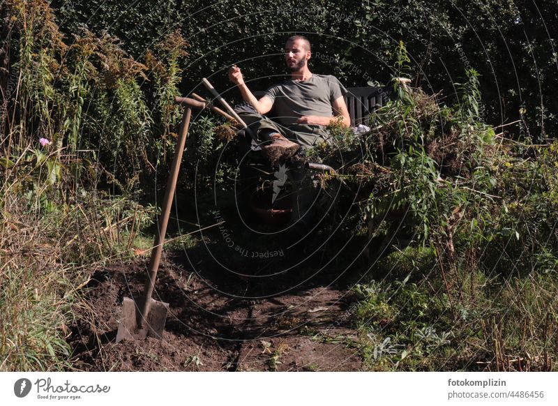 young gardener takes a break after digging up soil with a spade Gardener Gardening Man Spade do gardening Faded Earth Autumn Early fall Dig Break rest Young man
