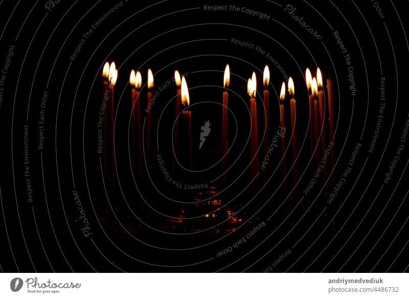 close up a lot of burning candles isolated on black background. candlelight flame fire night glow church religion christmas dark praying glowing religious
