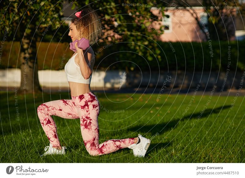 Personal trainer helping a young woman lift dumbells - a Royalty Free Stock  Photo from Photocase