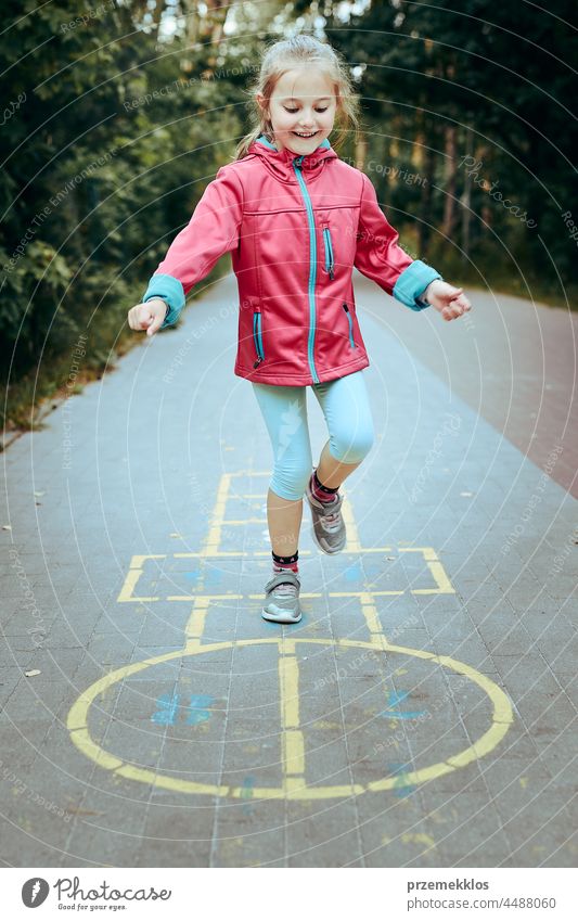 Active little girl playing hopscotch on playground outdoors jumping preschool game child fun chalk outside exercise joy kid active happy sidewalk enjoyment