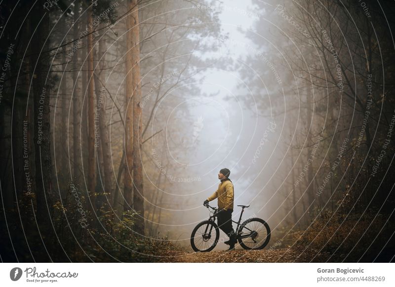 Young man taking a brake during biking through autumn forest action active activity adventure athlete bicycle bicycling bicyclist bike biker exercise extreme