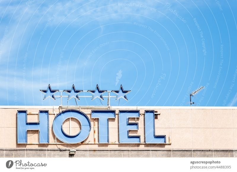 Top view of a hotel with a sign with the neon lights off that says "Hotel" and 4 stars above built tour tourism holiday facades business architecture metallic