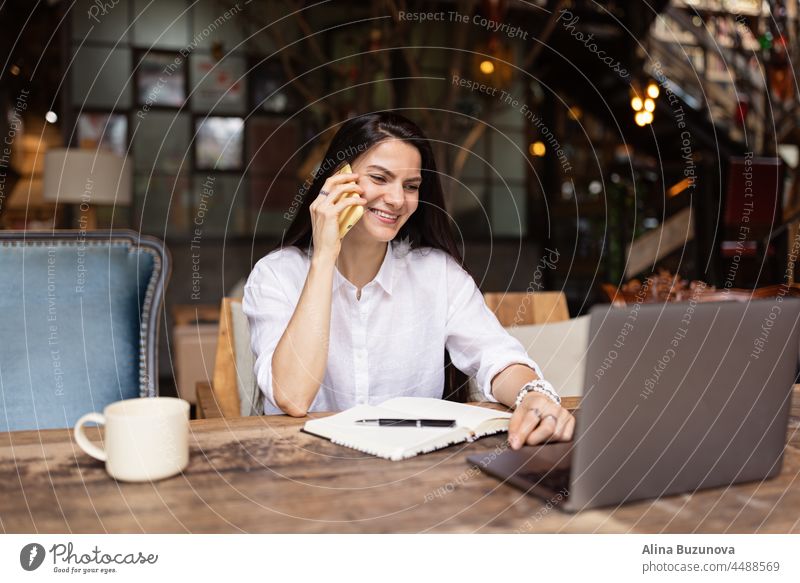 Young Caucasian business woman with long brunette hair working on laptop in cafe. College student using technology online businesswoman phone professional young