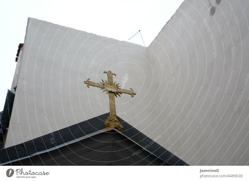 golden cross on black gable in front of white wall Crucifix Belief Faith and religion Spirituality Symbols and metaphors Holy from below Hope Christianity