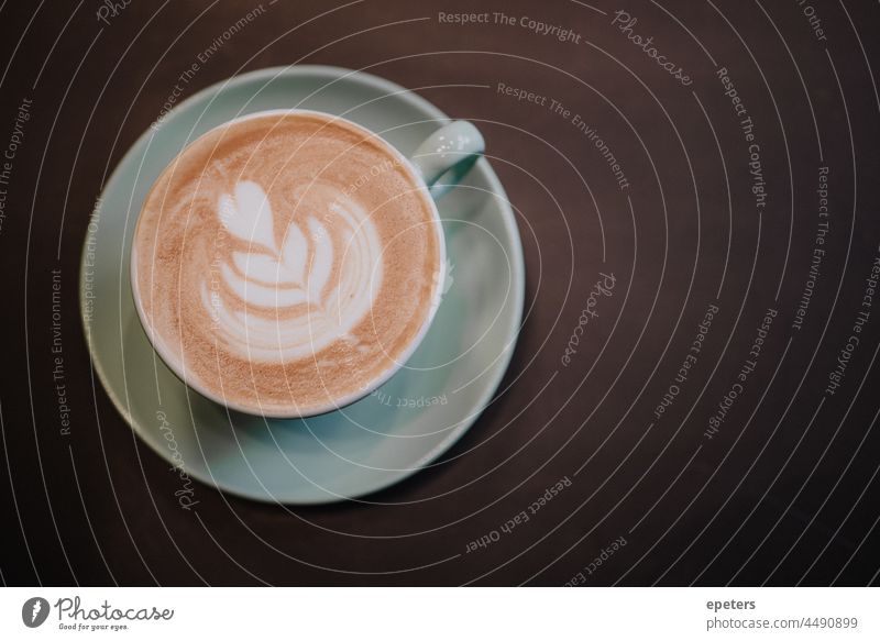 Top view of a cup of frothy coffee on a dark table brown cafe café cappuccino capuccino copy space flat lay flower green heart latte latte art latté latté art