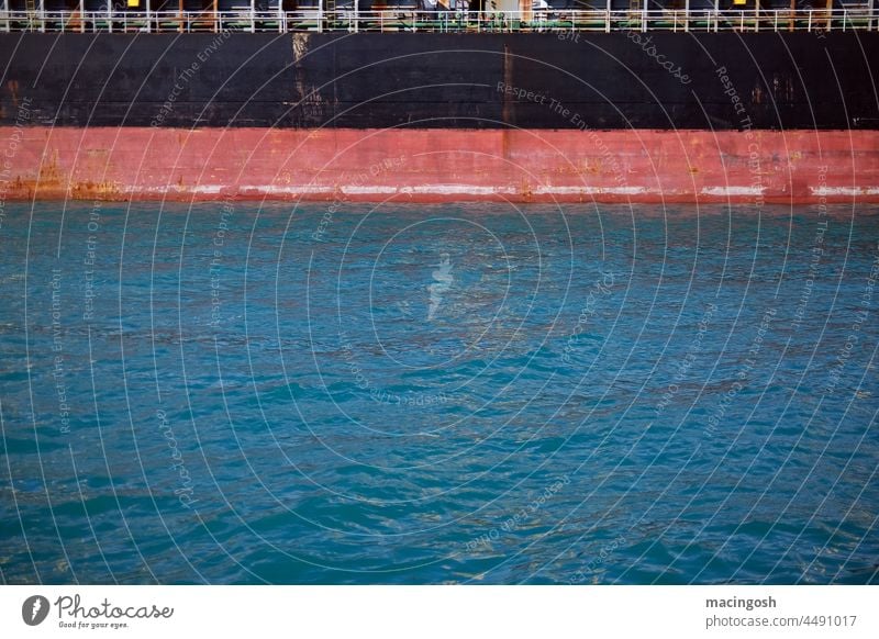 Ship's wall and water surface in the harbour Black Red Blue ship cargo ship Harbour Mooring place Drop anchor Unload loading Navigation logistics