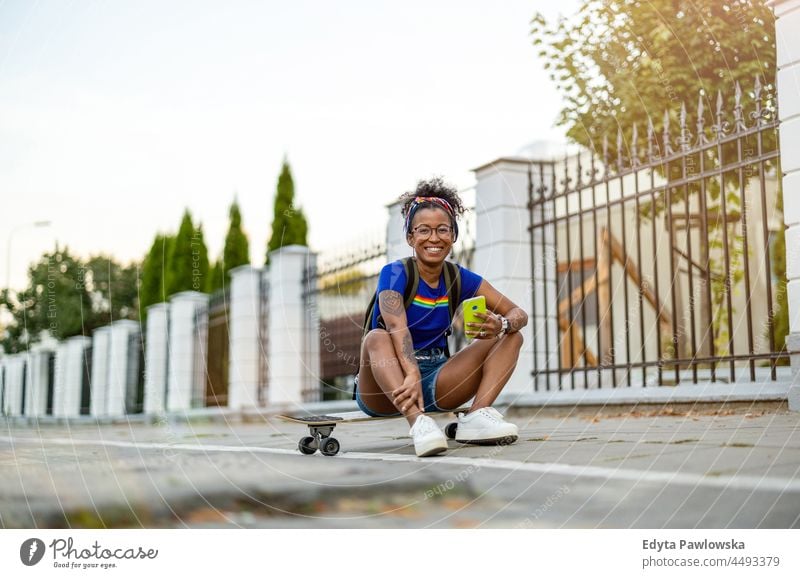Young woman sitting on skateboard in the city millennials eyeglasses curly joy outside colorful afro confident female beauty vacation travel satisfied