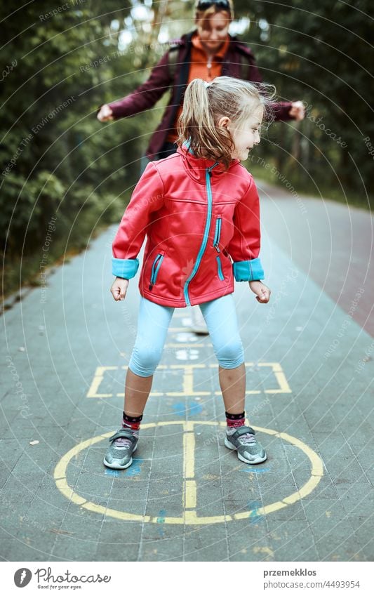 Active little girl playing hopscotch on playground outdoors jumping preschool game child fun chalk outside exercise joy kid active happy sidewalk enjoyment
