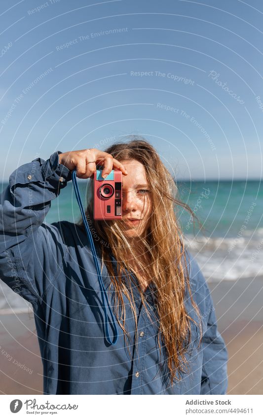 Woman taking photo on camera woman sea beach photo camera device sand summer water wet female shore take photo coast young gadget nature make face memory