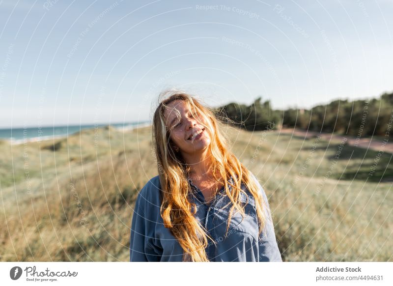 Happy woman standing in grassy meadow gesture summer happy nature field peaceful grimace smile glad female delight fun cheerful young lawn countryside positive