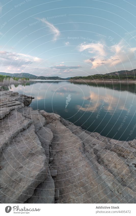 Stony shore near calm lake water rocky stone nature coast waterside lakeside hill environment scenic aqua flow river waterfront surface natural scene scenery