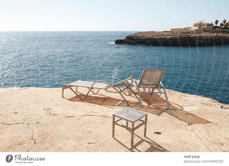 Sun loungers on the edge of a cliff in the morning light overlooking the horizon of the sea Ocean vacation travel Tourism Summer vacation Warmth tranquillity