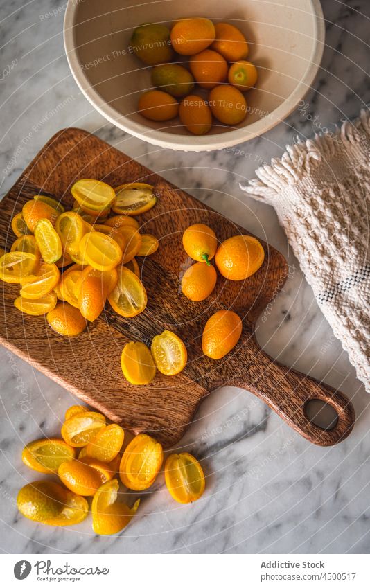 Heap of kumquats on cutting board fruit organic natural healthy food citrus vitamin kitchen fresh ripe wooden chopping board nutrition marble orange tasty pile