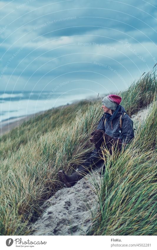 Woman sitting with dog in the dunes on the North Sea coast Dog Labrador duene Nature vacation Denmark Grass Sand Beach Autumn Vacation & Travel Sky Ocean