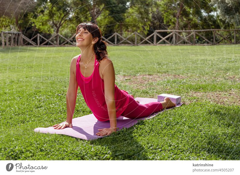 Young pretty yoga girl portrait, doing yoga poses on green mat indoors.  Beautiful blond woman doing pilates exercises. Woman in sports suit  meditating. Woman stretching alone, flexible and slim. Stock Photo