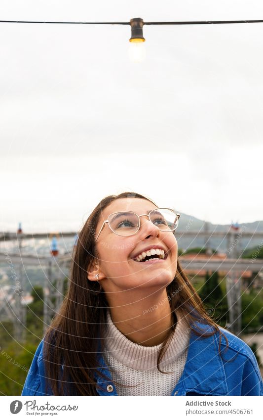 Excited woman under garland in park excited amusement cheerful dream smile happy delight expressive fairground carousel activity attraction amazed youth laugh