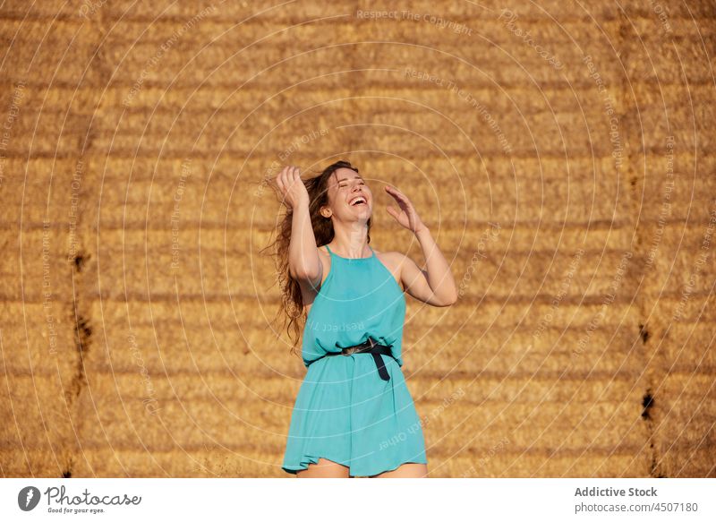 Laughing woman with flying hair near haystacks wind laugh flip hair fun expressive rural playful joy female positive glad cheerful optimist dry happy humor lady