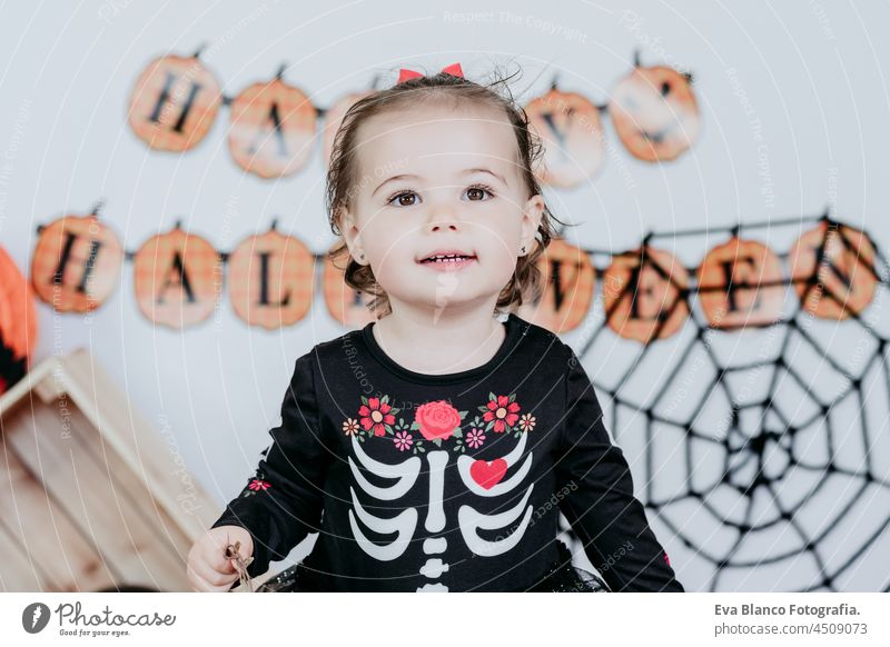 portrait of beautiful one year old caucasian girl in halloween costume at home with Halloween decoration, Lifestyle indoors. Halloween party concept. happy
