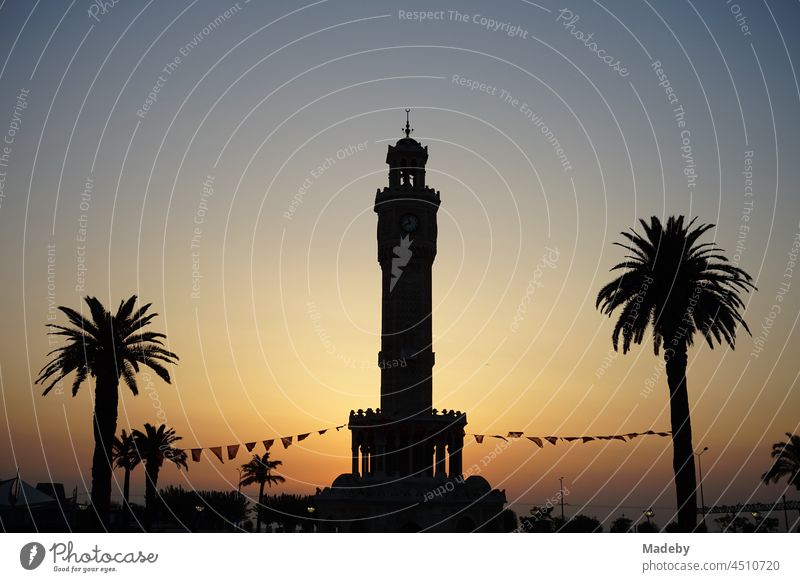 The clock tower of Izmir with Mediterranean palm trees in the light of the setting sun at Konak Square in old Smyrna on the Aegean Sea in Turkey Places