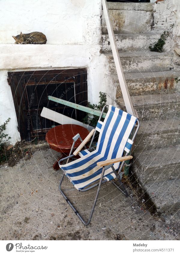 Striped camping chair in the yard next to a staircase with sleeping cat in the old town of Foca at the Aegean Sea near Izmir in Turkey Chair Folding chair