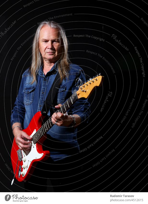 elderly man with long gray hair plays the electric guitar grey long hair caucasian sound music guitarist male hobby artist instrument musician player performer
