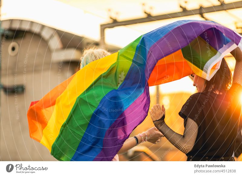 Happy young couple waving rainbow flag homosexual couple love together romantic queer non-binary gender fluid lgbt equality millennials gender-blend transgender
