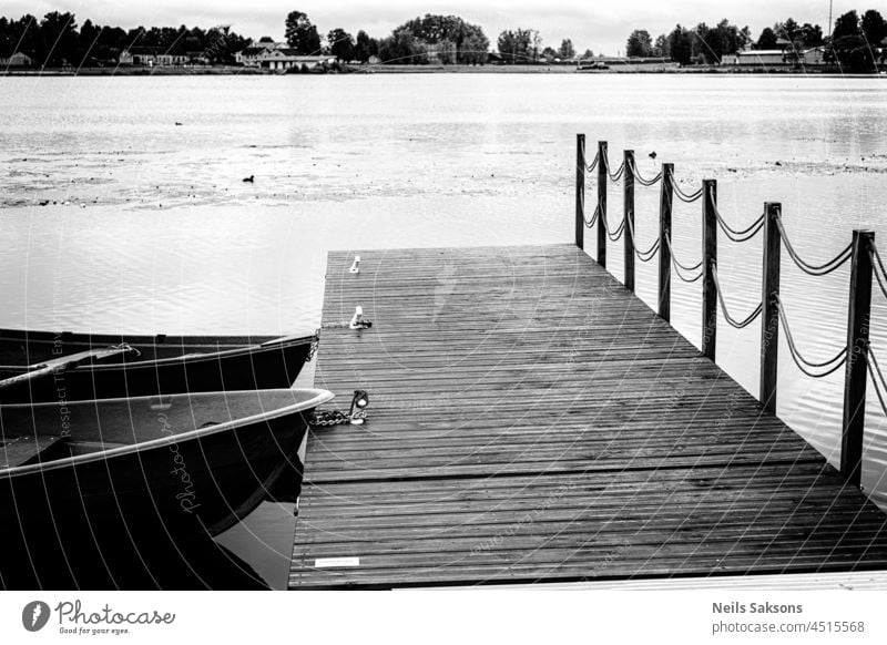 Two old rowing boats at jetty footbridge, monochrome black and white abstract background beach beautiful boating calm canoeing clouds dirty dock floating grungy