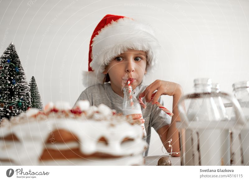 Good Christmas morning. A blond boy in a red Santa hat is having Breakfast, drinking milk santa food sweet white christmas newyear celebration december dessert