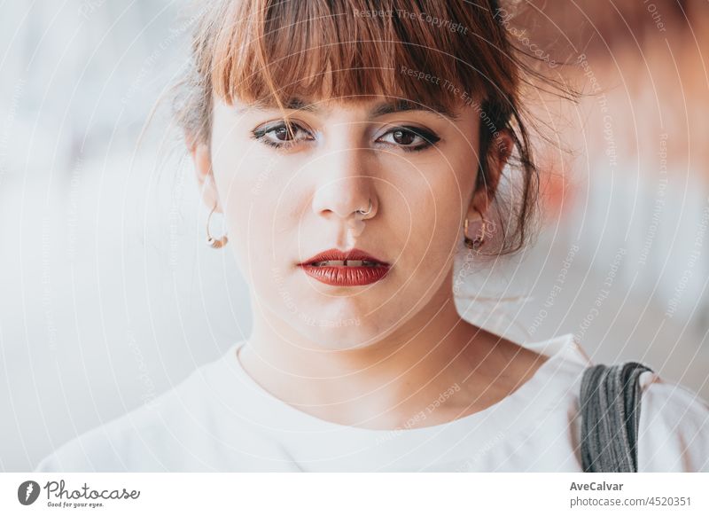 Close up portrait of a young woman looking straight to camera with a serious face and red lips, make up on eyes, hipster conceptual image, young people person