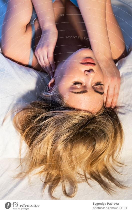 Beautiful woman laying on the bed. Woman keeping eyes closed relaxing on bed wearing bralette top. beautiful relaxation comfortable portrait home bedroom face