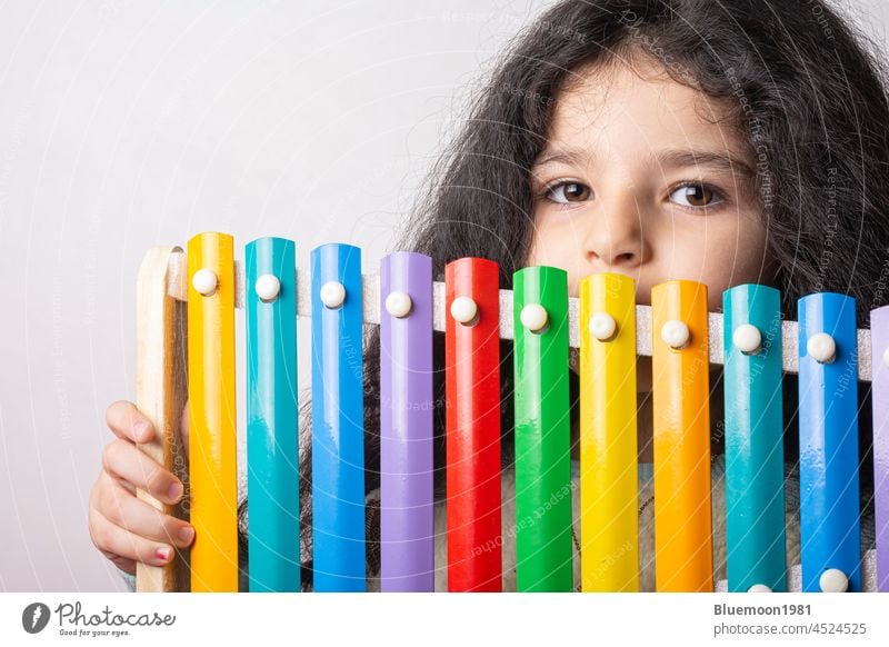 Little girl portrait with xylophone in hand looking in camera with expression, childhood memories four years music tools colorful metal instrument little girl