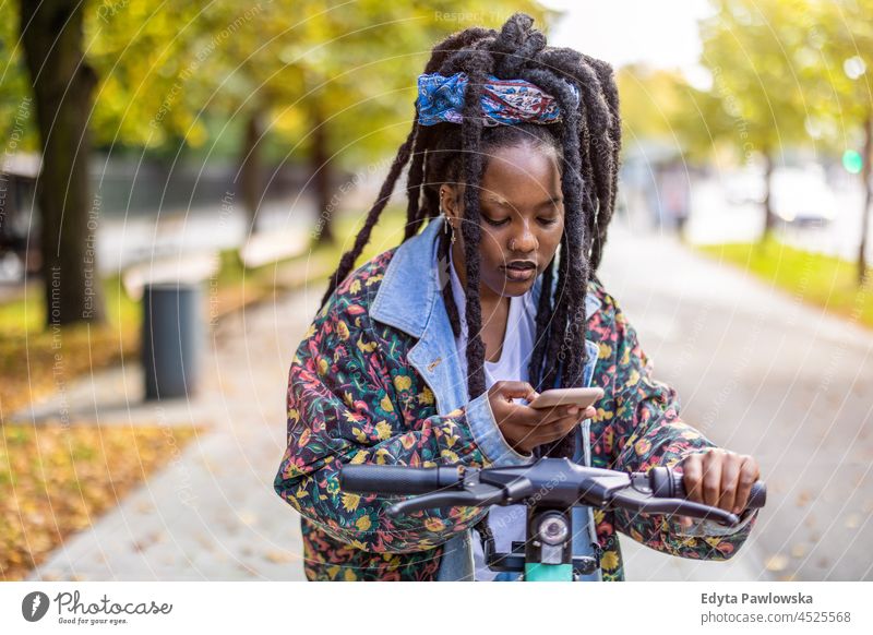 Activating electric scooter from smartphone unaltered natural real people authentic body inclusivity body positive one person hipster girl hairstyle dreadlocks
