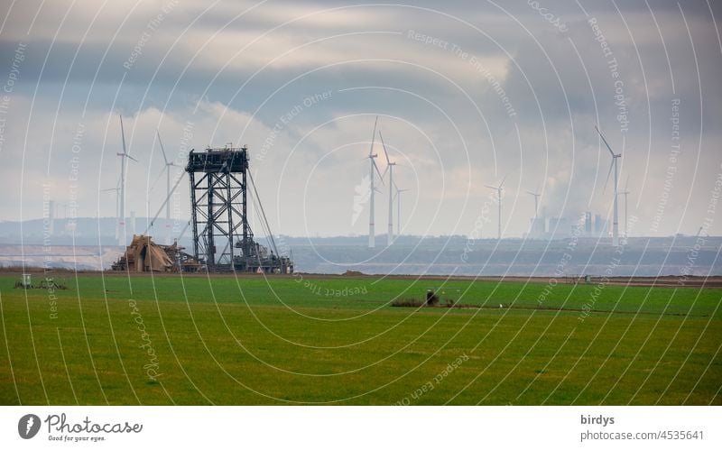 Bucket-wheel excavator in the Garzweiler2 open-cast lignite mine, a lignite-fired power plant and wind turbines in the background Soft coal mining