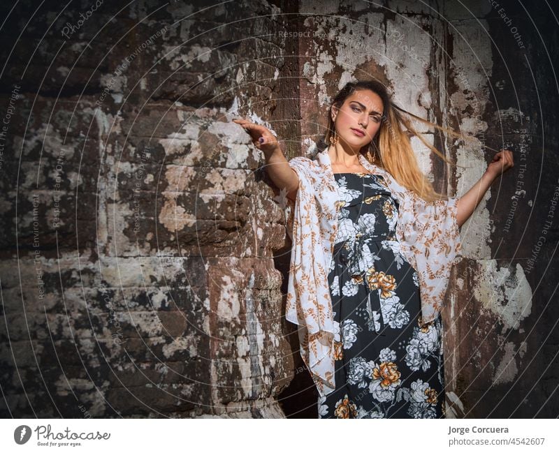 attractive woman leaning on a stone wall touching her hair. concept enjoy life fun young happy vacation holiday smile happiness outdoor cute caucasian people